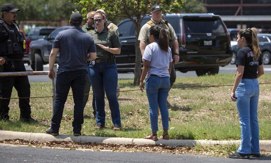 May 24, 2022, Uvalde, Texas, USA: A law enforcement officer tells people Tuesday afternoon, May 24, 2022 that Uvalde High School is secure after a school shooting at the nearby Robb Elementary School  ...