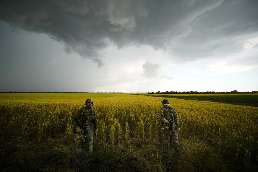ARCHIV - 14.06.2022, Ukraine, NA: Russische Soldaten bewachen ein Gebiet neben einem Weizenfeld, w