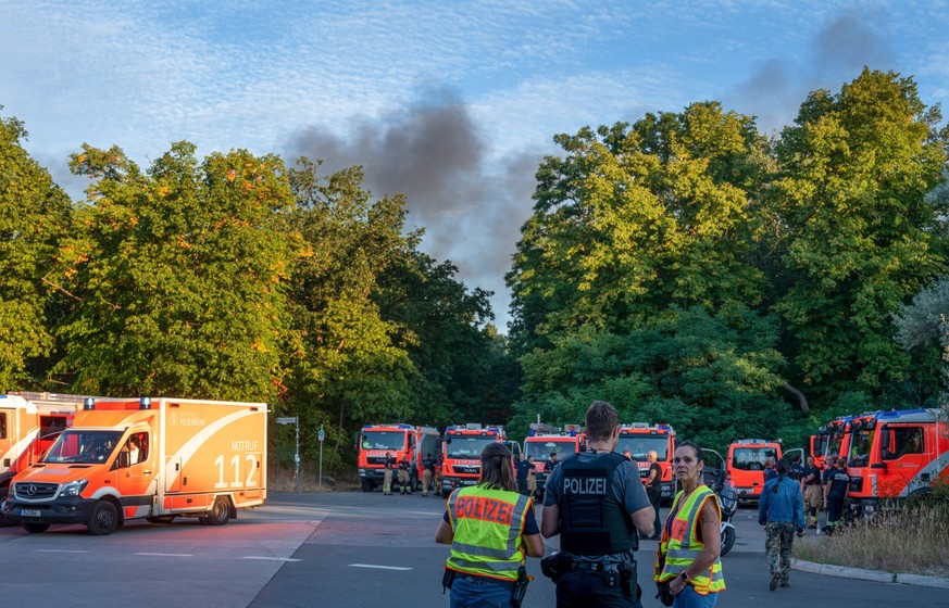 04.08.2022, Berlin: Polizeibeamte und Feuerwehrfahrzeuge stehen am Kronprinzessinnenweg in Berlin. Im Berliner Grunewald ist nach einer unbeabsichtigten Explosion auf dem dortigen Sprengplatz am Donne ...