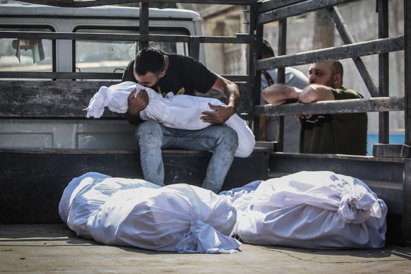 ARCHIV - 12.10.2023, Palästinensische Gebiete, Gaza-Stadt: Ein palästinensischer Mann küsst die Leiche eines bei israelischen Luftangriffen getöteten Kindes auf der Ladefläche eines Fahrzeugs am Al-Sh ...