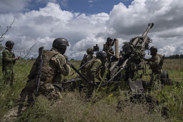 14.07.2022, Ukraine, Charkiw: Ukrainische Soldaten Laden Munition in eine von den USA gelieferte M777 Haubitze, um auf russische Stellungen zu schie