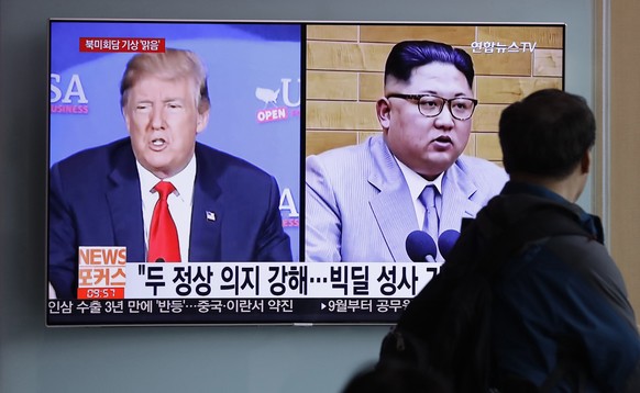 FILE - In this May 11, 2018, file photo, a man watches a TV screen showing file footage of U.S. President Donald Trump, left, and North Korean leader Kim Jong Un with onscreen letters reading &quot;Su ...