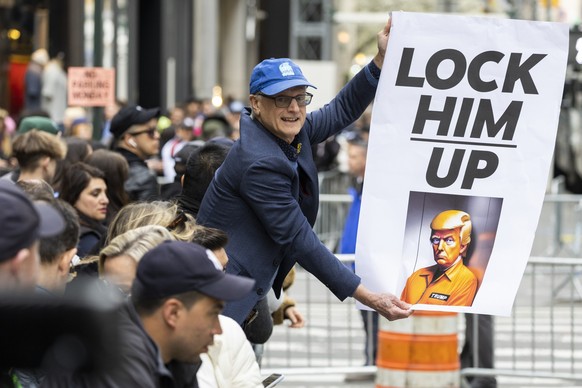 A protester holds a placard outside Trump Tower in New York on Monday, April 3, 2023. Former President Donald Trump is expected to be booked and arraigned on Tuesday on charges arising from hush money ...