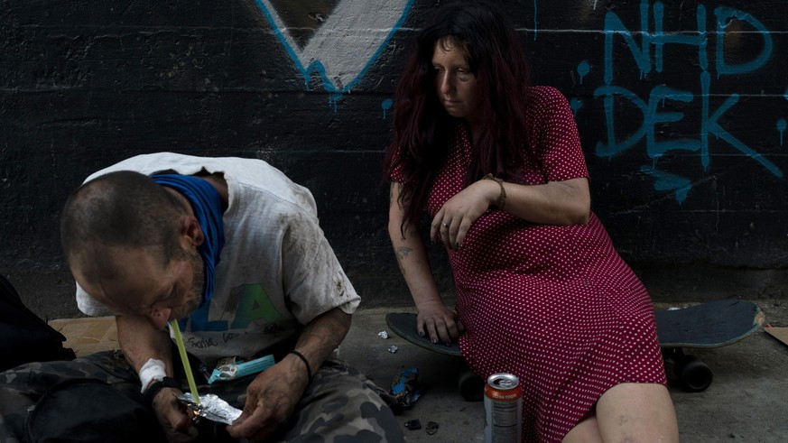 Jenn Bennett, who is high on fentanyl, sits on her skateboard with a visible black eye as her friend, Jesse Williams, smokes the drug in Los Angeles, Tuesday, Aug. 9, 2022. Use of fentanyl, a powerful ...