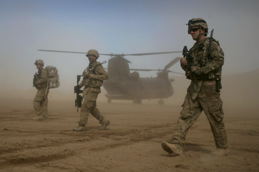 FILE - U.S. soldiers, part of the NATO- led International Security Assistance Force (ISAF), walk as a U.S. Chinook helicopter is seen on the back ground in Shindand, Herat, west of Kabul, Afghanistan, ...