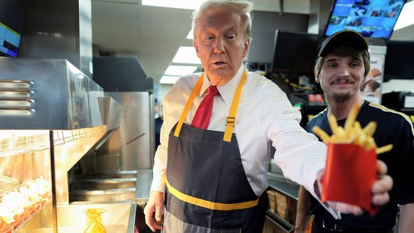 dpatopbilder - 20.10.2024, USA, Philadelphia: Donald Trump (l), US-Präsidentschaftskandidat der Republikaner und ehemaliger US-Präsident, gibt eine Pommes-Bestellung aus, nachdem er mit einem Angestel ...