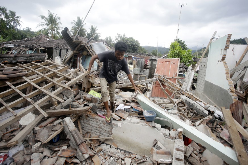 A man walks through debris from Sunday's earthquake in West Lombok, Indonesia, Saturday, Aug. 11, 2018. Scientist say the powerful Indonesia earthquake that killed more than 300 people lifted the isla ...
