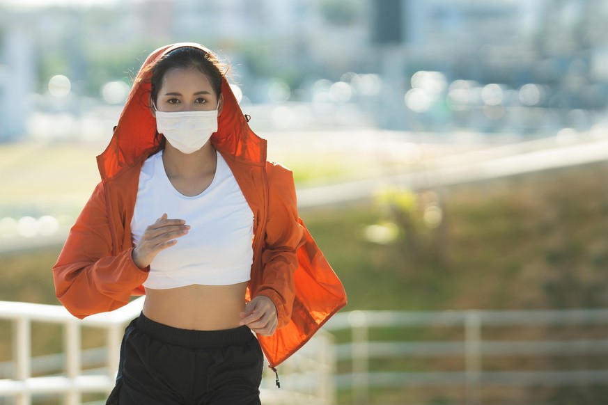 Woman runners morning exercise she wears a nose mask. Protection against dust and viruses