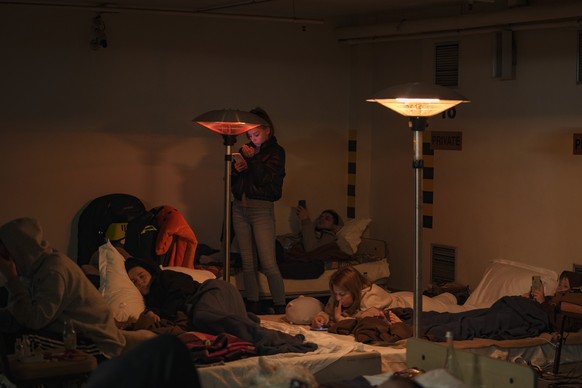 People lie on mattresses in a hotel underground parking turned into a bomb shelter during an air raid alert in Kyiv, Ukraine, Sunday, Feb. 27, 2022. Terrified men, women and children sought safety ins ...