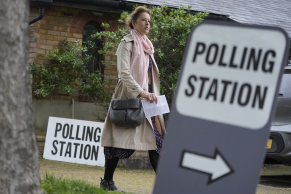 FILE - A woman holds her voting card as she arrives to vote in London in local elections, Thursday, May 2, 2024. U.K. voters are set to cast ballots in a national election on July 4, passing judgment  ...