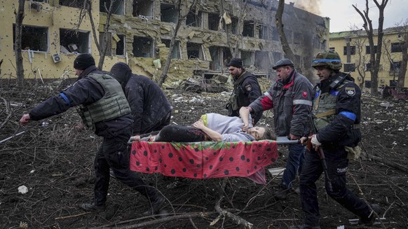 FILE - Ukrainian emergency employees and volunteers carry an injured pregnant woman from the damaged by shelling maternity hospital in Mariupol, Ukraine, March 9, 2022. The Russian airstrike on a chil ...