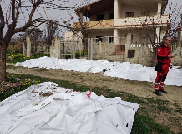 February 26, 2023, CROTONE: Italian rescuers stand near the body of the victims of the fishing boat at the Steccato of Cutro, in the Crotone area, Italy, 26 February 2023. The approximately fifty surv ...