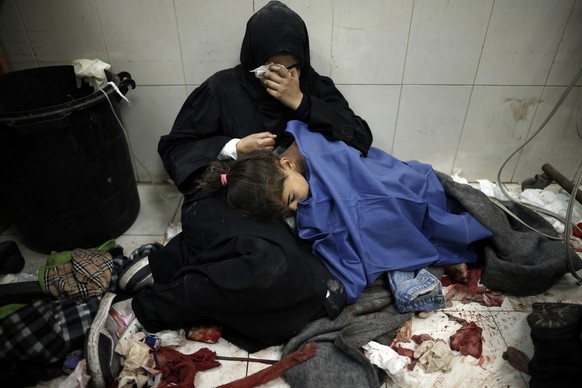 A Palestinian woman cries as she sits next to her girl wounded in the Israeli bombardment of the Gaza Strip while receiving treatment at the Nasser hospital in Khan Younis, Southern Gaza Strip, Monday ...