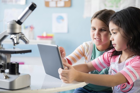 Caucasian girls sharing digital tablet in classroom, Kaukasische Maedchen digitale Tablette im Klassenzimmer teilen || Modellfreigabe vorhanden
