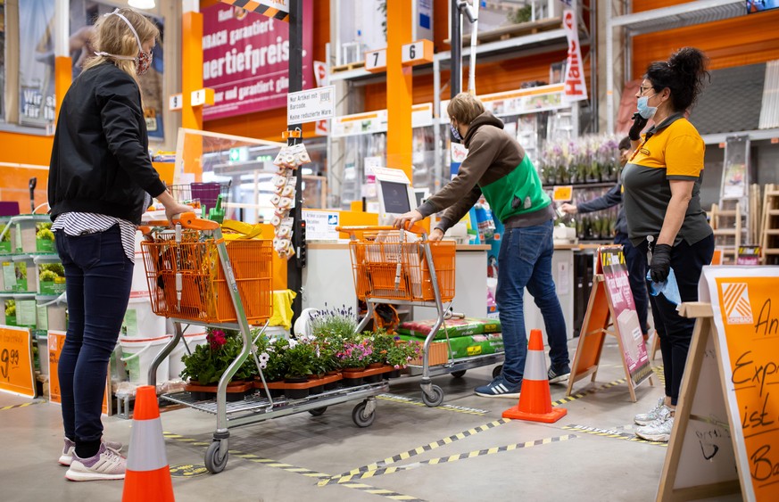 20.04.2020, Bayern, München: Kunden stehen in einem Hornbach-Baumarkt an einer Kasse. Ab dem 20.04.2020 dürfen Bau- und Gartenmärkte in Bayern wieder öffnen. Andere Geschäfte mit einer Verkaufsfläche  ...