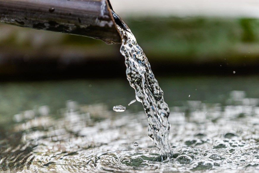 Purification water fountain in Kyoto, Japan with liquid running from spout faucet