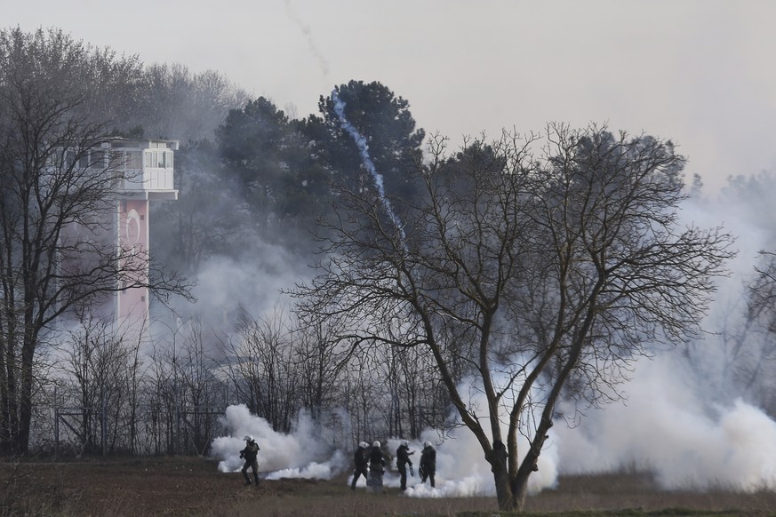 Greek riot police police is seen through smoke during clashes at the Greek-Turkish border in Kastanies, Evros region, on Friday, March 6, 2020. Clashes erupted on the Greek-Turkish border Friday morni ...