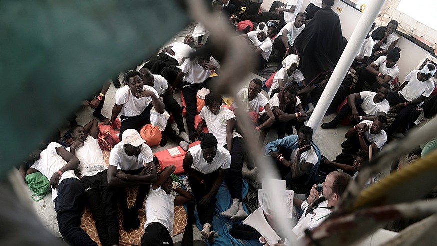 Migrants sit on the deck of the MV Aquarius, a search and rescue ship run in partnership between SOS Mediterranee and Medecins Sans Frontieres in the central Mediterranean Sea, June 12, 2018. Karpov / ...
