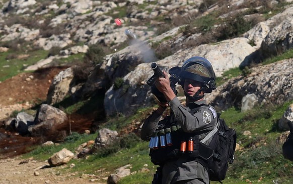 Westjordanland, Ausschreitungen in Nablus 220121 -- NABLUS, Jan. 21, 2022 -- A member of the Israeli border police fires a tear gas canister at Palestinian protesters during a protest against the expa ...