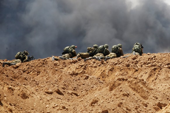 Smoke rises as Israeli soldiers are seen on the Israeli side of the border with the Gaza Strip, Israel, May 14, 2018. REUTERS/Baz Ratner