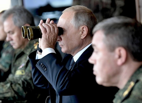 FILE - Russian President Vladimir Putin looks through a binocular as Russian Defense Minister Sergei Shoigu, left, and the Head of the General Staff of the Armed Forces of Russia and First Deputy Defe ...