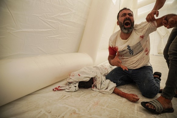 October 9, 2023, Palestinian Territories, Gaza City: EDS NOTE GRAPHIC IMAGE DEPICTING DEATH: A Palestinian man reacts next to the body of his nephew, who was killed in Israeli airstrikes on the Soussi ...