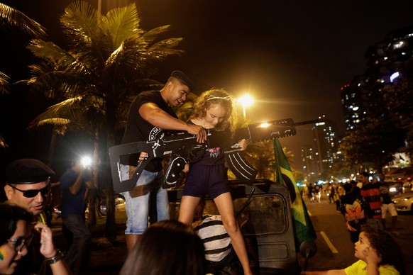 Supporters of Jair Bolsonaro, far-right lawmaker and presidential candidate of the Social Liberal Party (PSL), hold a cardboard gun, after Bolsonaro wins the presidential race, in Rio de Janeiro, Braz ...
