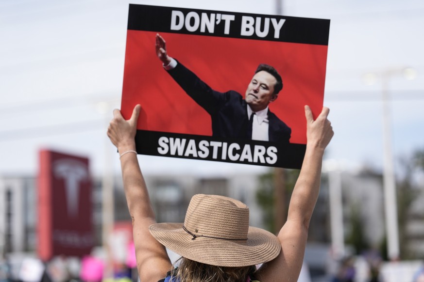 Jennifer Walker stands with other demonstrators during a protest of automaker billionaire CEO, Elon Musk near a Tesla vehicle dealership, Saturday, March 8, 2025, in Decatur, Ga. (AP Photo/Mike Stewar ...