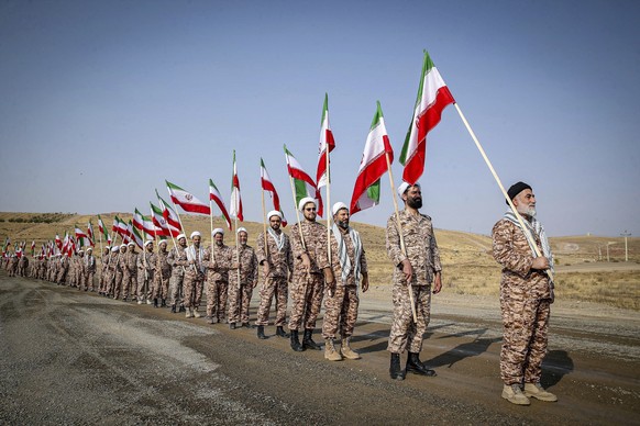 In this photo provided by Revolutionary Guard's ground force on Monday, Oct. 17, 2022, clerics hold Iranian flags while attending a maneuver in northwestern Iran. (Iranian Revolutionary Guard's Ground ...