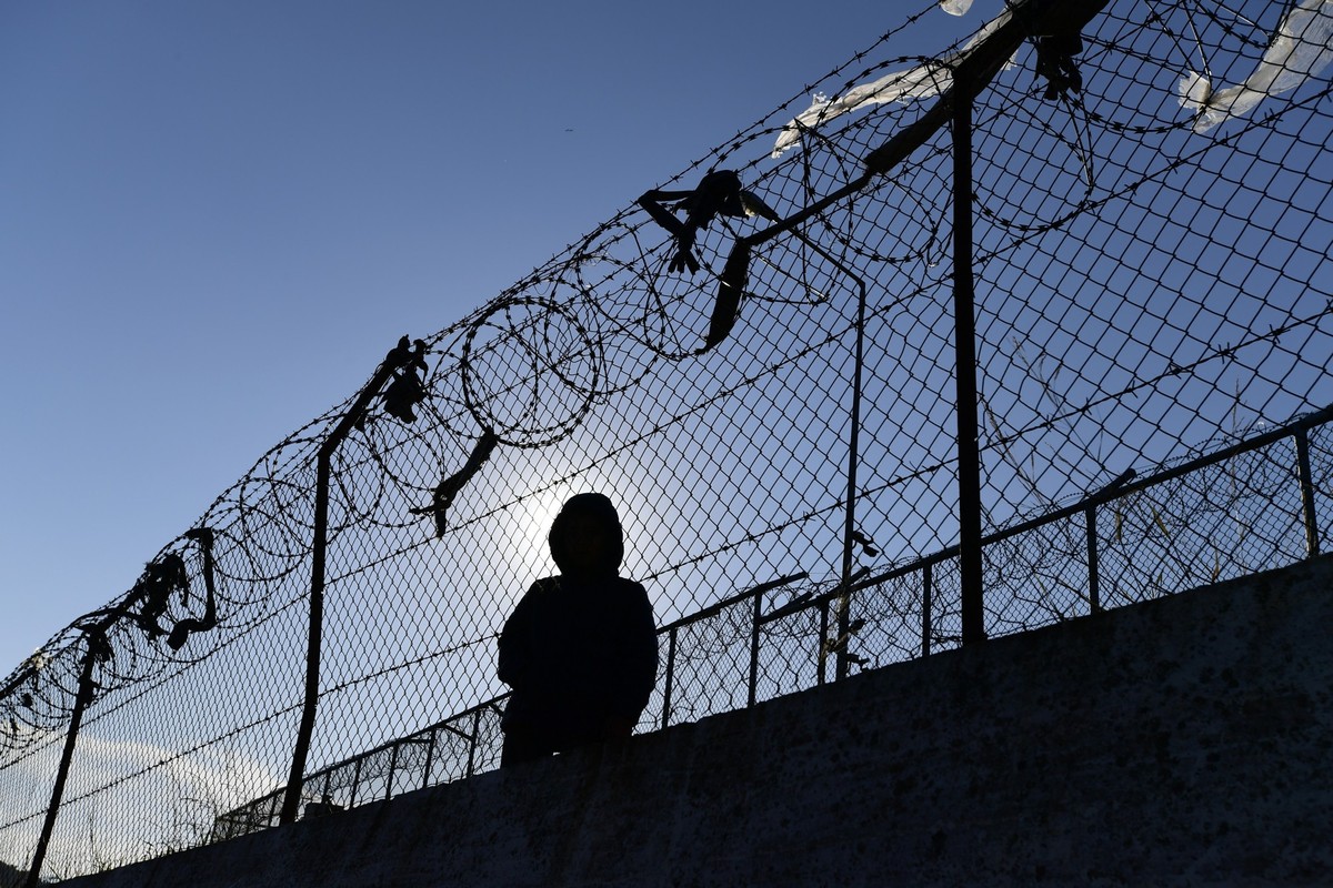 ARCHIV - 24.02.2020, Griechenland, Moria: Ein Migrant sitzt neben einem Zaun des Fl