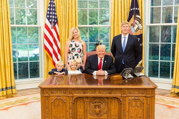 U.S. President Donald Trump and Vice President's Chief of Staff Nick Ayers (R) and his wife Jamie Floyd with their children pose for pictures in the Oval Office at the White House in this social media ...
