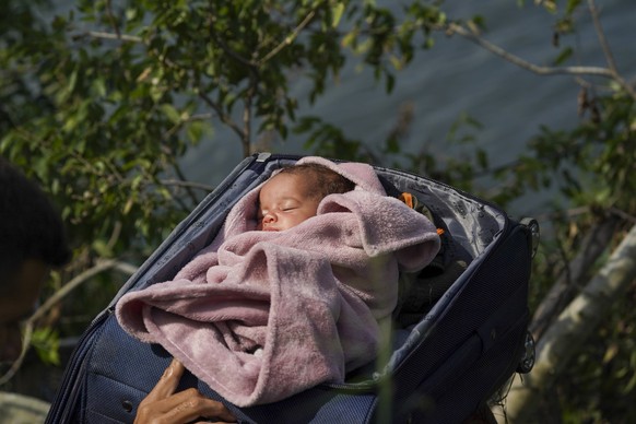 10.05.2023, Mexiko, Matamoros: Migranten überqueren den Rio Grande in die USA mit einem Baby in einem Koffer. Am 11. Mai fällt eine umstrittene Abschiebepraxis, die sogenannte Titel-42-Regelung, weg.  ...