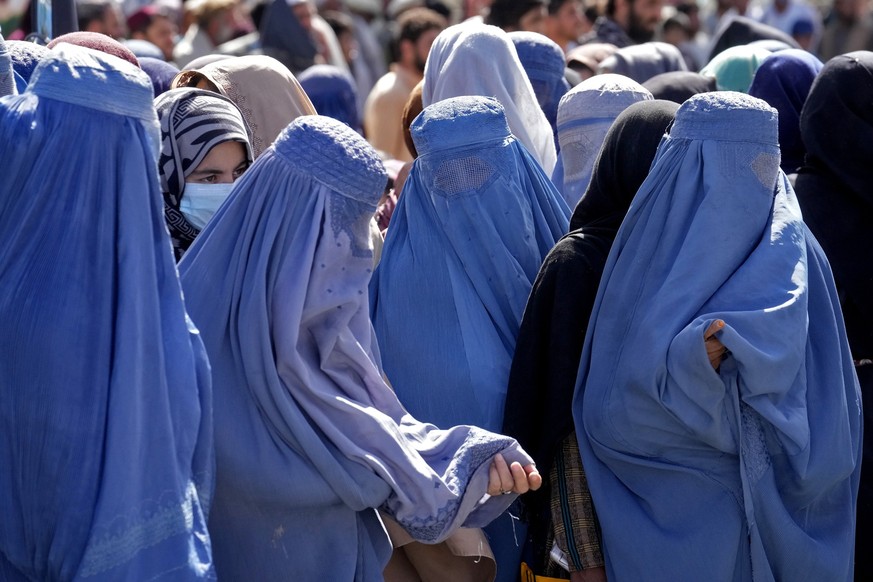 ARCHIV - 15.08.2022, Afghanistan, Kabul: Frauen in Burkas warten auf Lebensmittelrationen, die von einer humanit