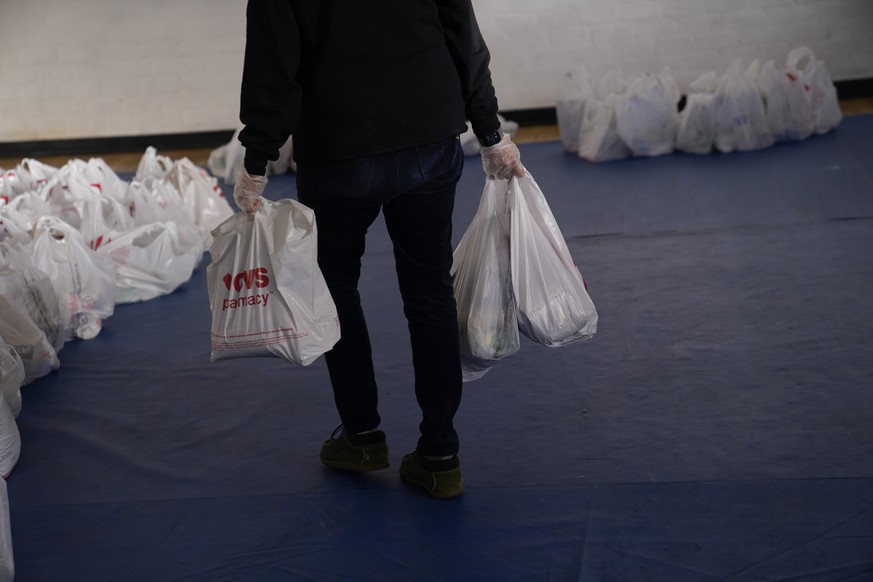 FILE - In this Dec. 17, 2020, file photo a volunteer prepares bags of groceries for people in need at Los Angeles Boys &amp; Girls Club in the Lincoln Heights neighborhood of Los Angeles. (AP Photo/Ja ...