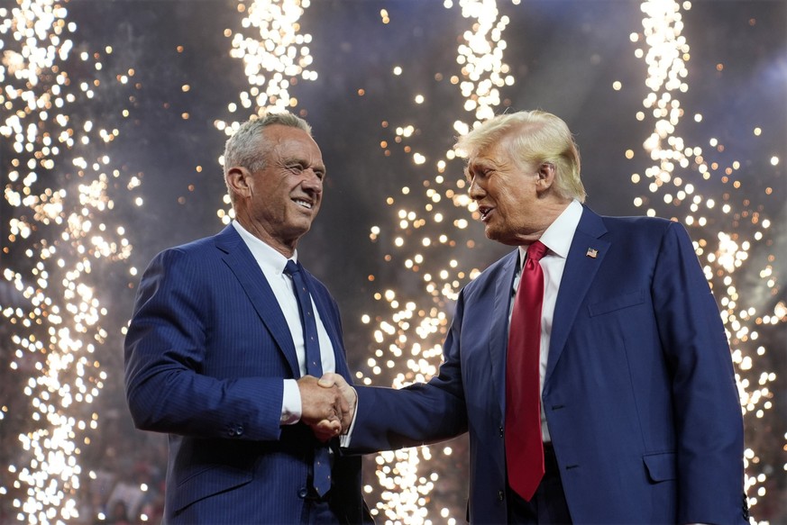 Republican presidential nominee former President Donald Trump shakes hands with Independent presidential candidate Robert F. Kennedy Jr. at a campaign rally at the Desert Diamond Arena, Friday, Aug. 2 ...