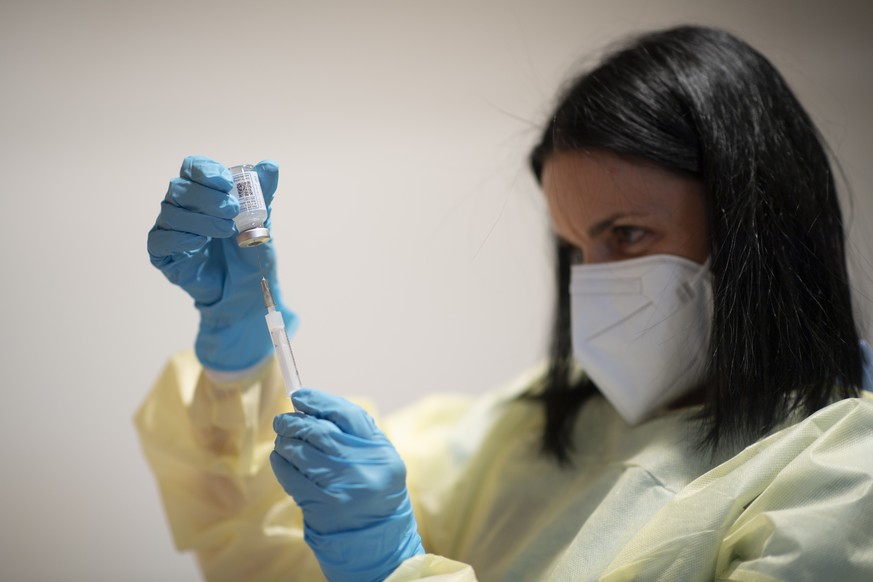 25.01.2021, Schweiz, Davos: Eine Mitarbeiterin mit Mund-Nasen-Schutz bereitet im Kongresszentrum eine Corona-Impfung vor. Am 25.01.2021 nehmen im Kanton Graub