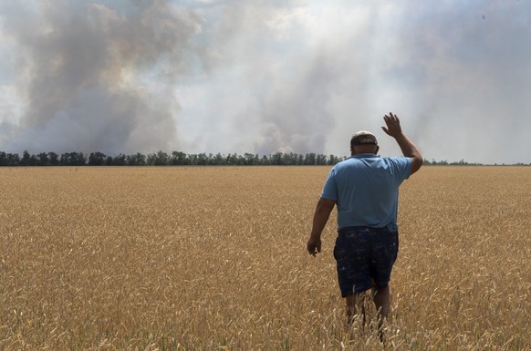 Ein Landwirt blickt auf sein brennendes Feld nahe der Frontlinie bei Dnipropetrovsk in der Ukraine.