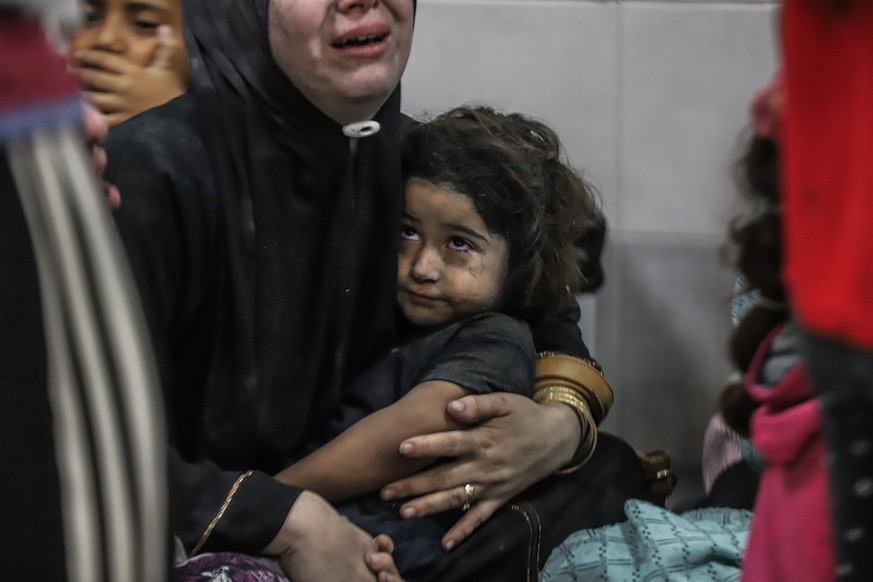 17.10.2023, Palästinensische Gebiete, Gaza-Stadt: Verletzte Palästinenser mit einem Kind warten warten auf medizinische Versorgung im Al-Shifa Krankenhaus, nachdem sie im Ahli Arab Krankenhaus im Gaza ...