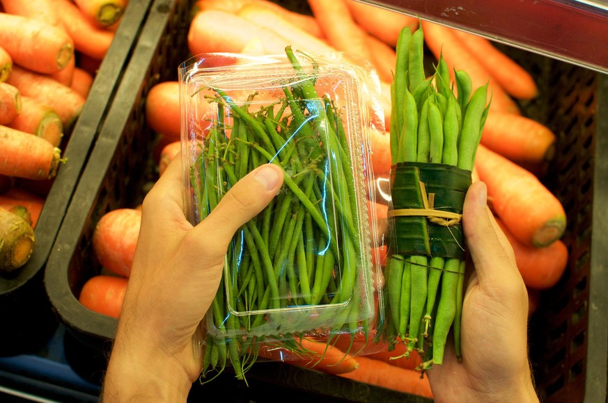 Beans bundled in a plastic package and other beans wrapped in Banana leaf held in female hands. This is an excellent solution how replace plastic packaging and reduce the waist of it - Bali, Indonesia
