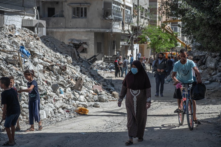 GAZA CITY, GAZA - MAY 15: Palestinians walk past damaged buildings in al-Shati Refugee Camp west of Gaza City on May 15, 2021 in Gaza City, Gaza. More than 125 people in Gaza and eight people in Israe ...
