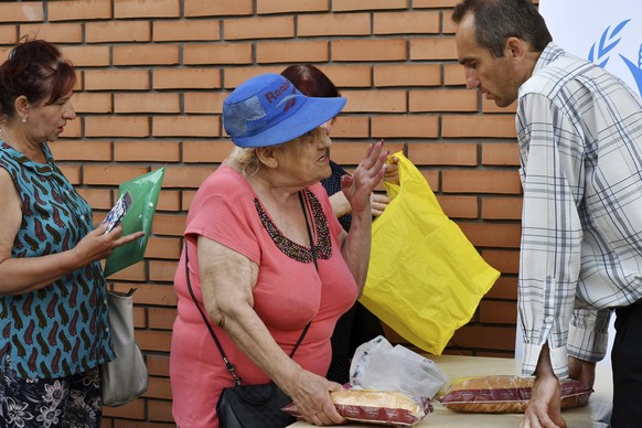 04.08.2022, Ukraine, Saporischschja: Frauen stehen an einer Verteilerstelle f