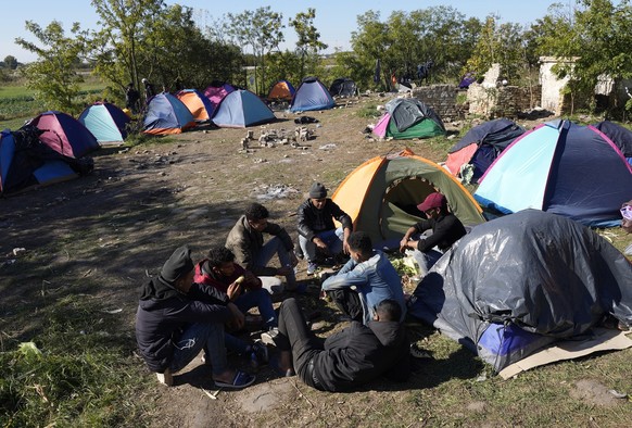20.10.2022, Serbien, Horgos: Migranten sitzen neben Zelten in einem behelfsm��igen Lager in der N�he der Grenze zwischen Serbien und Ungarn. Serbien liegt im Herzen der sogenannten Balkanroute und hat ...
