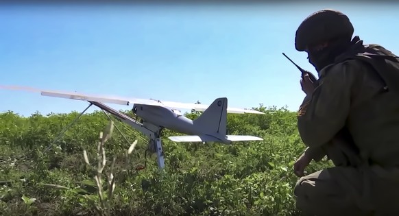 This handout photo taken from video released by Russian Defense Ministry Press Service on Monday, Aug. 8, 2022, shows a Russian serviceman preparing a Orlan-10 reconnaissance drone to launch at an und ...
