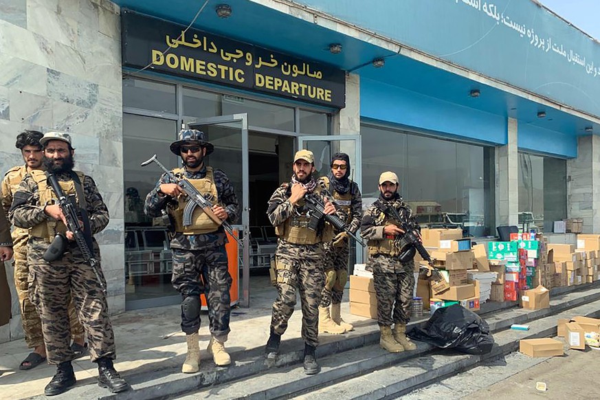 FILE - In this Aug. 31, 2021 file photo, Taliban fighters stand guard inside the Hamid Karzai International Airport after the U.S. withdrawal in Kabul, Afghanistan. Taliban authorities will allow betw ...