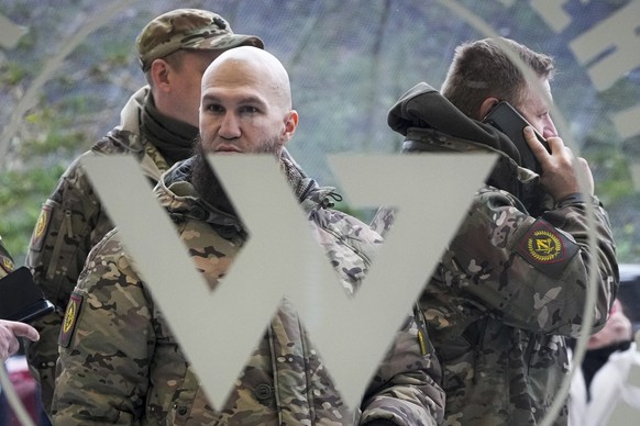 FILE - Visitors wearing military camouflage stand at the entrance of the &#039;PMC Wagner Centre&#039;, which is associated with businessman and founder of the Wagner private military group Yevgeny Pr ...
