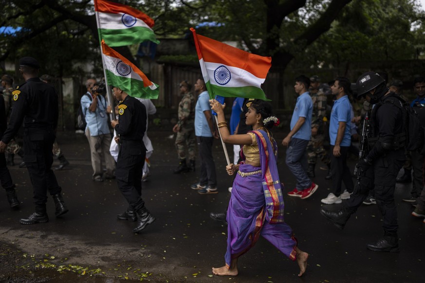 A girl walks carrying Indian flag along with army soldiers during a ceremony to celebrate 75 years of India&#039;s Independence in Mumbai, India, Sunday, Aug. 14, 2022. The world’s largest democracy i ...