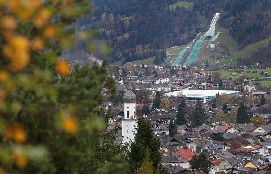 ARCHIV - 04.11.2013, Bayern, Garmisch-Partenkirchen: Blick auf Garmisch-Partenkirchen mit der Skisprungschanze (hinten. Der heftige Corona-Ausbruch im bayerischen Garmisch-Partenkirchen soll auf eine  ...