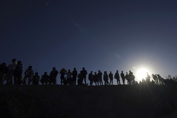 ARCHIV - 30.03.2023, Mexiko, Ciudad Juarez: Migranten stehen auf der mexikanischen Seite der Grenze zwischen den USA und Mexiko am Ufer des Rio Grande. In Zentralmexiko sollen 50 Migranten aus einem B ...