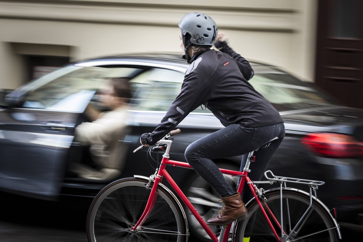 Gestellte Szene zum Thema Verkehrssicherheit: Ein Autofahrer oeffnet die Fahrertuer, waehrend ein Radfahrer eng daran vorbeifaehrt und sich darueber aufregt. Berlin, 13.02.2018. Berlin Deutschland *** ...
