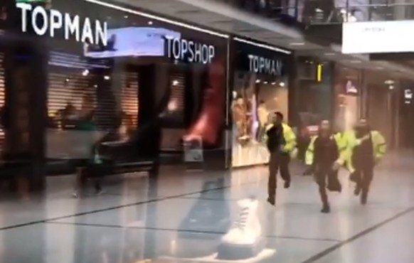 Polizisten laufen durch ein Einkaufszentrum in Manchester.
